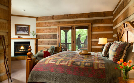 couple talking on a balcony outside their suite with gas fireplace, king size bed and jetted tub