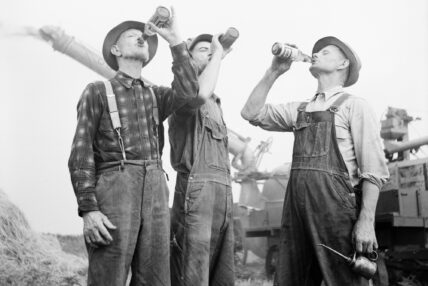 vintage photo of three men wearing overalls drinking beer together