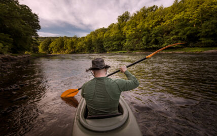 man with river hat kayaking in the Clarion River with yellow oar