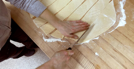 woman cutting flatten out dough for homemade ham pot pie