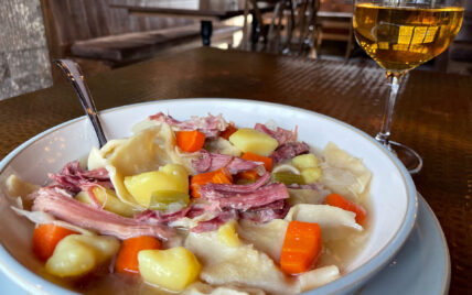 ham pot pie soup with a glass of wine on copper table