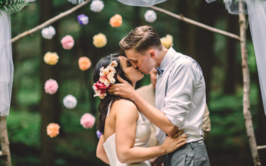 Wedding couple kissing under a decorated arch during their elopement at Gateway Lodge in Cook Forest, Pennsylvania.