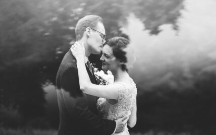 black and white photo of bride and groom dancing with reflection of water