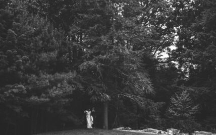 black and white image of wedding couple coming out of the forest at Gateway Lodge