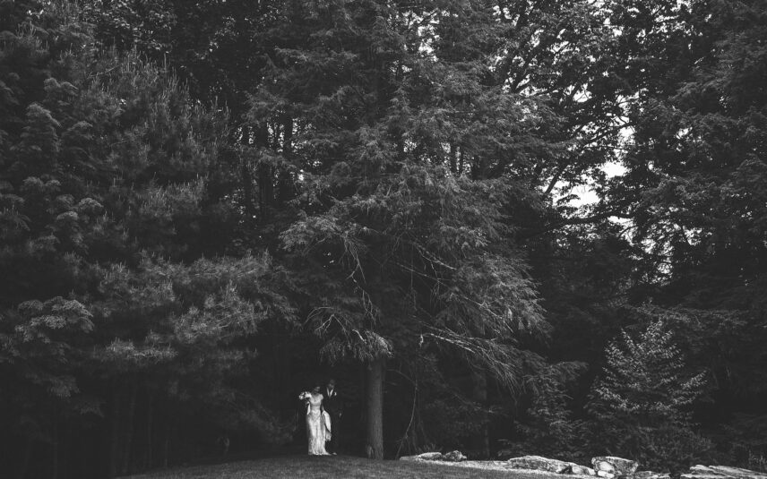 black and white image of wedding couple coming out of the forest at Gateway Lodge
