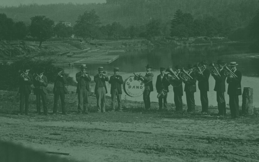 Vintage photograph of thirteen musicians in top hats playing trumpets on a boardwalk along the Clarion River in Cooksburg, Pennsylvania; the central musician holds a drum labeled 'COOK'S BAND, COOKSBURG, PA', suggesting a historical musical connection to the region near Gateway Lodge.