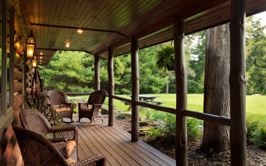 Spacious outdoor porch of the Forest Meeting Facility and Retreat Center at Gateway Lodge in Cook Forest, Pennsylvania, overlooking an open yard area surrounded by the lush trees of Cook Forest, perfect for breakout sessions or relaxation.