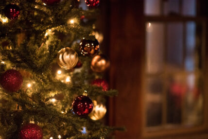 close-up of a lit Christmas tree decorated with gold and red bulbs in the restaurant dining room at Gateway Lodge