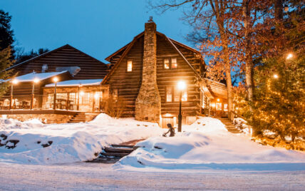 exterior of Gateway Lodge entrance at night during winter, featuring the outdoor dining deck