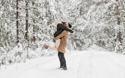 young woman being lifted and kissed by a young man on a snowy trail in Cook Forest State Park