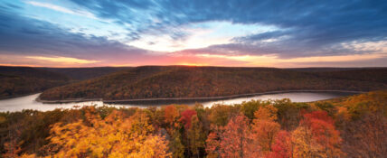 panoramic view of Allegheny National Forest at sunrise, featuring autumn leaves and the Allegheny River in the background under clear blue skies