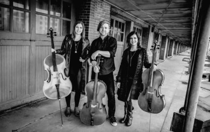 three musicians from the Cello Fury band, holding cellos, preparing to perform at Gateway Lodge's New Year's Eve weekend in Cook Forest, Pennsylvania